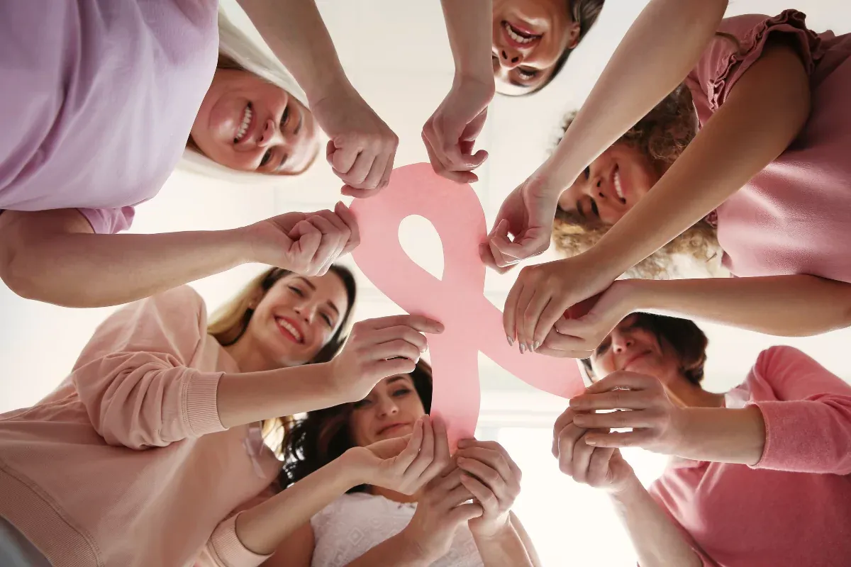 Varias mujeres juntas sosteniendo un lazo rosa