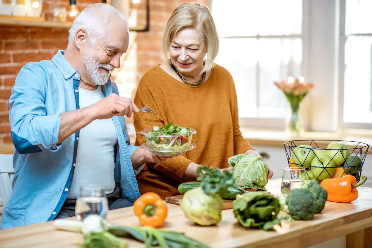 Pareja de ancianos preparando comida saludable (ensalada)