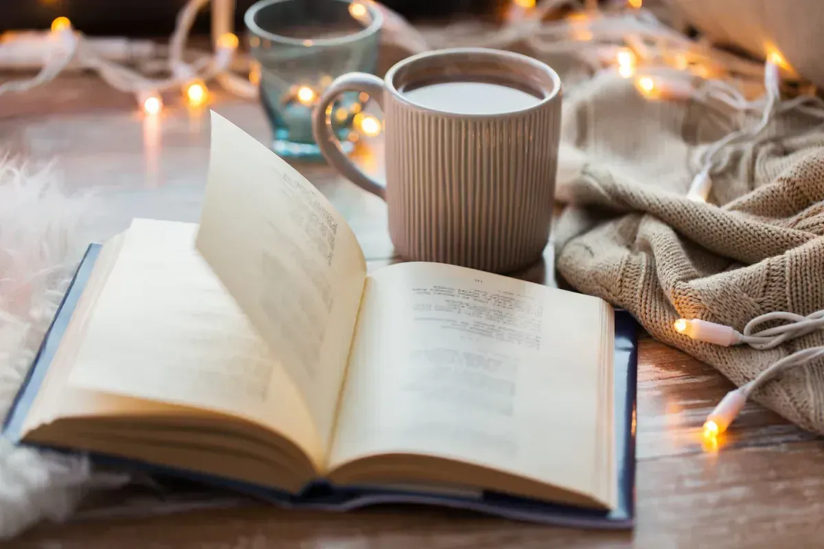 Una mesa con un libro abierto y una taza de café