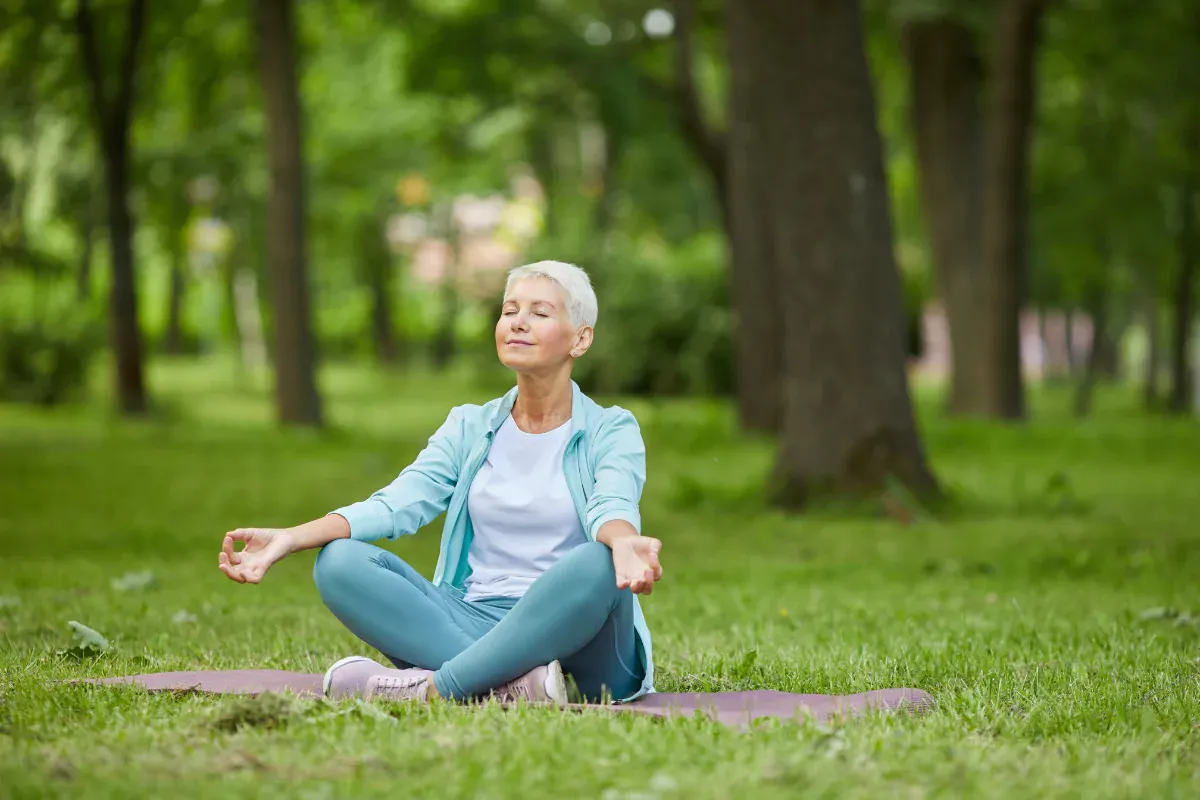 Una anciana sentada en el césped, meditando