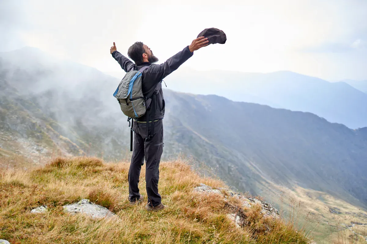 Un niño en la cima de una montaña con los brazos abiertos