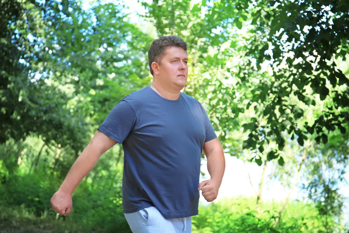 Un hombre caminando en la naturaleza, representando una vida activa y saludable