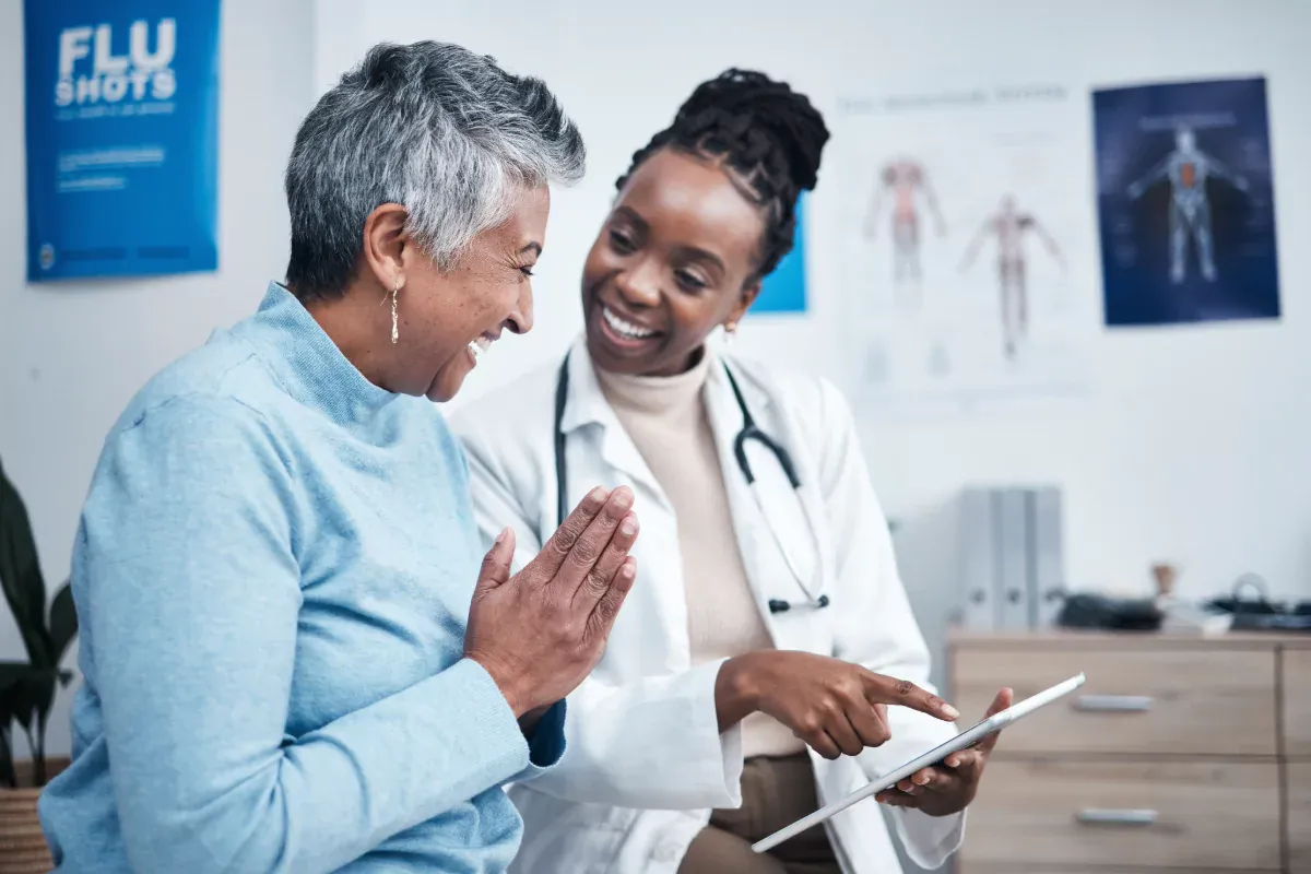 Una doctora hablando con su paciente, ambas felices.